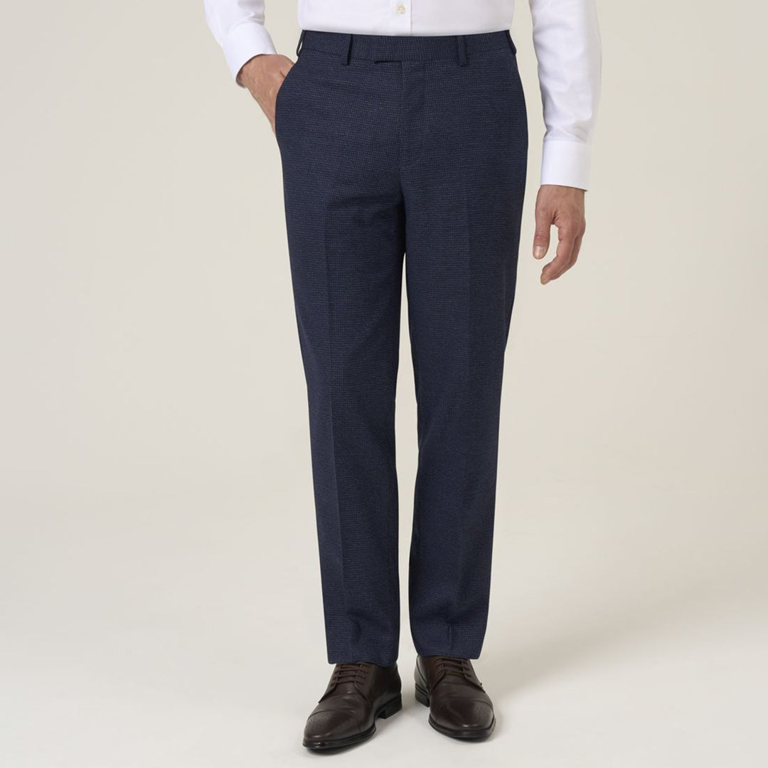 Navy blue dress pants worn with a white shirt and brown shoes on a beige background