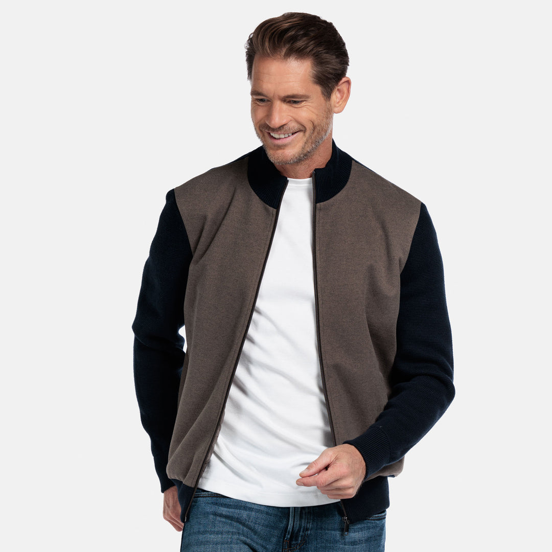 Man wearing a brown and navy cardigan with a white t-shirt underneath on a light gray background