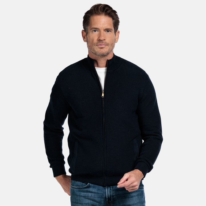 Man wearing a navy zip-up cardigan on a white background