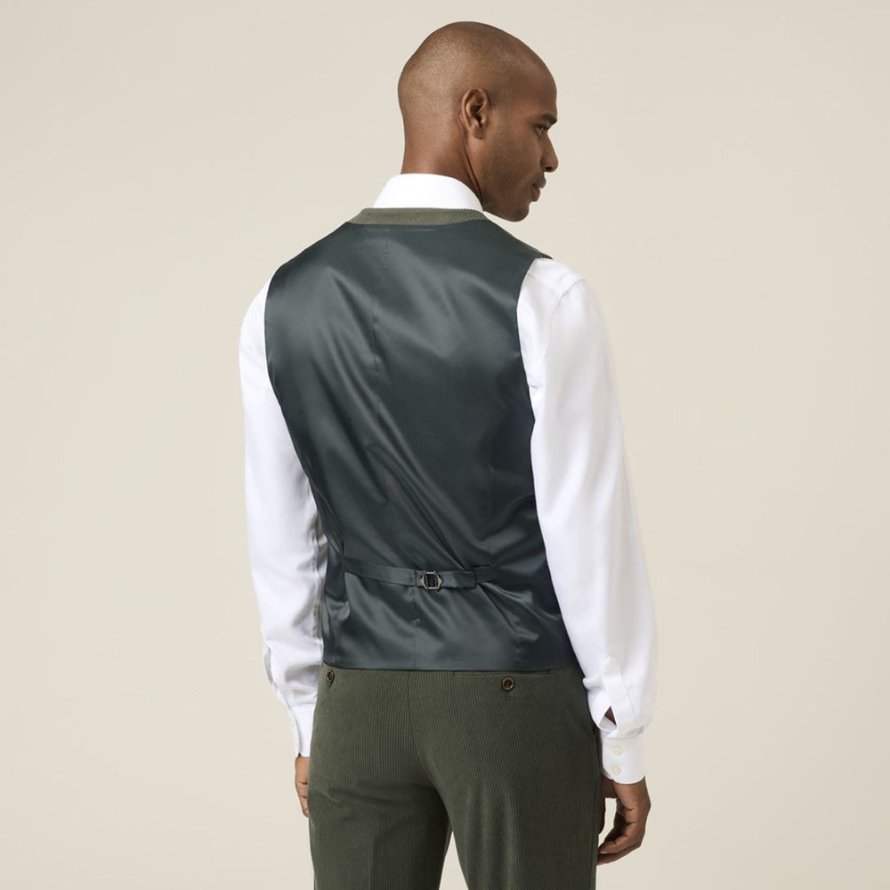 Man wearing a dark green vest over a white shirt on a beige background