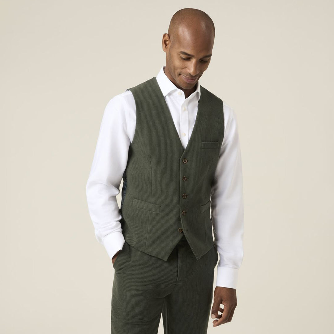 Man wearing a green vest over a white shirt on a beige background