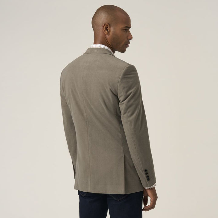 Man wearing a gray blazer and white shirt on a beige background
