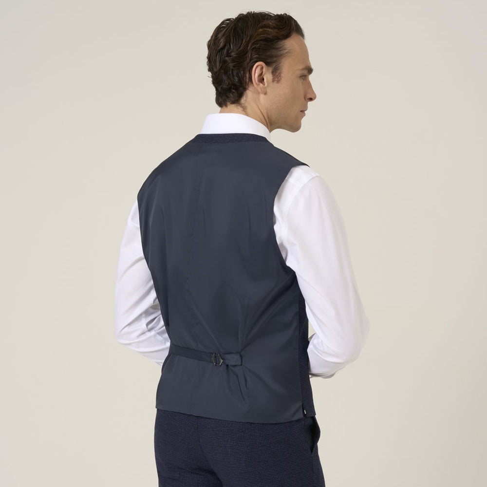 Man wearing a dark gray vest over a white shirt on a beige background