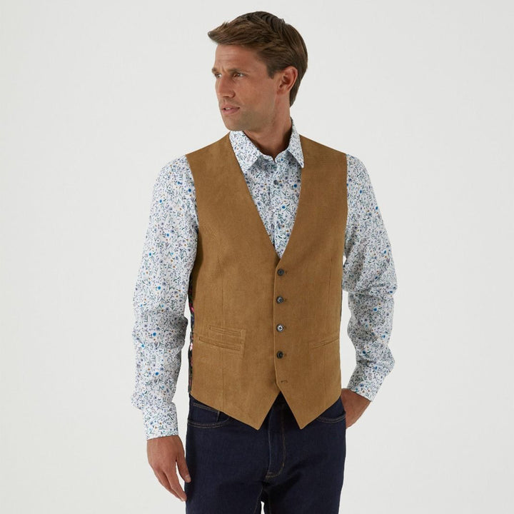 Man wearing a brown vest over a patterned shirt on a white background