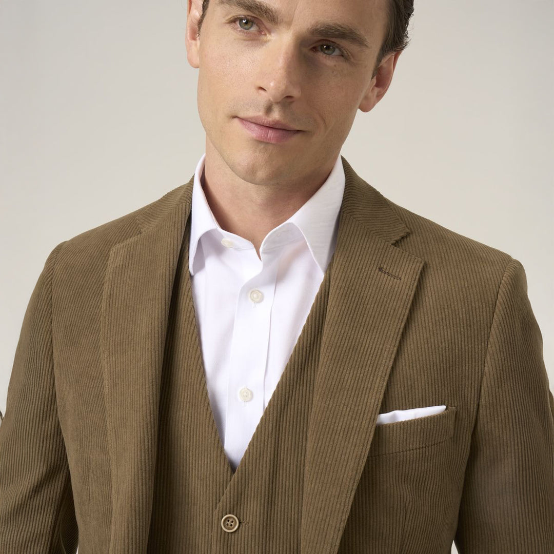 Man wearing a brown suit with a white shirt on a plain background
