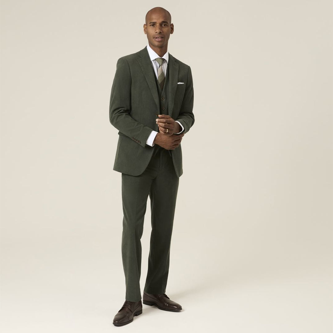 Man wearing a green suit with a white shirt and brown shoes on a beige background