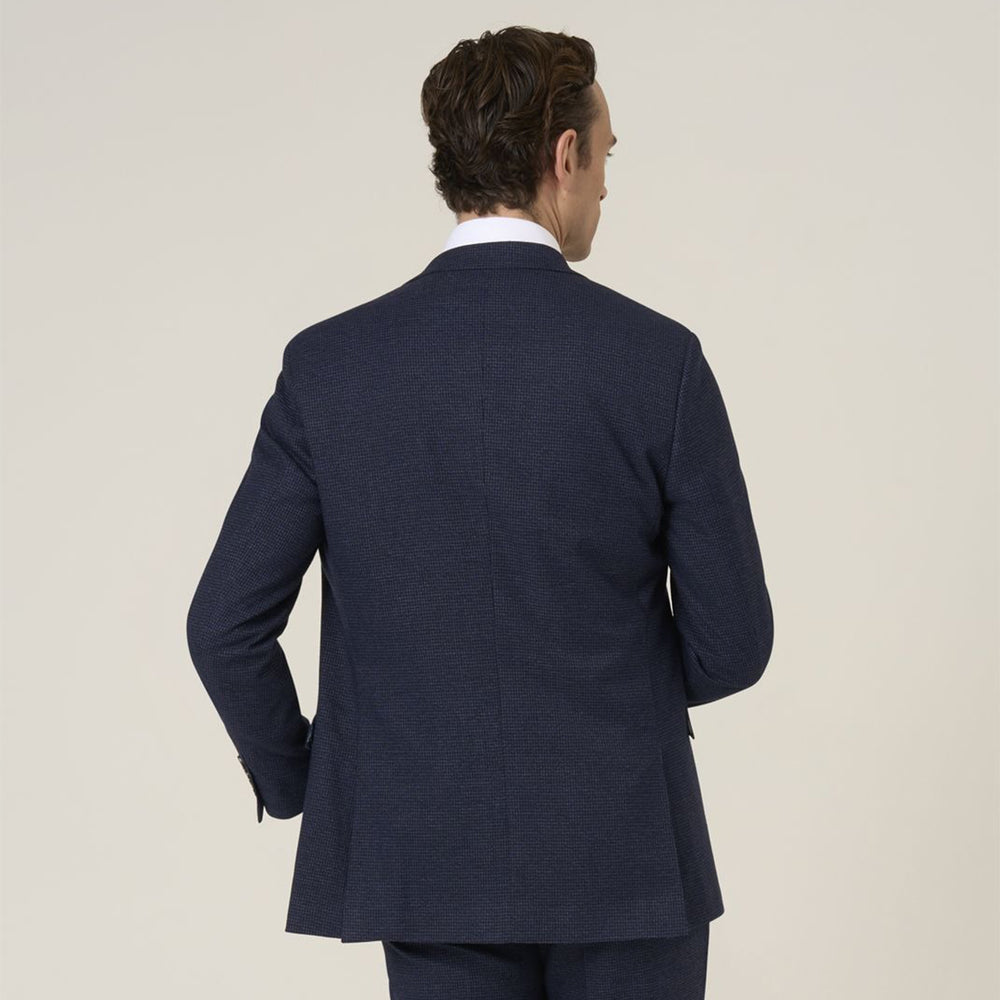 Man wearing a navy suit jacket on a light beige background