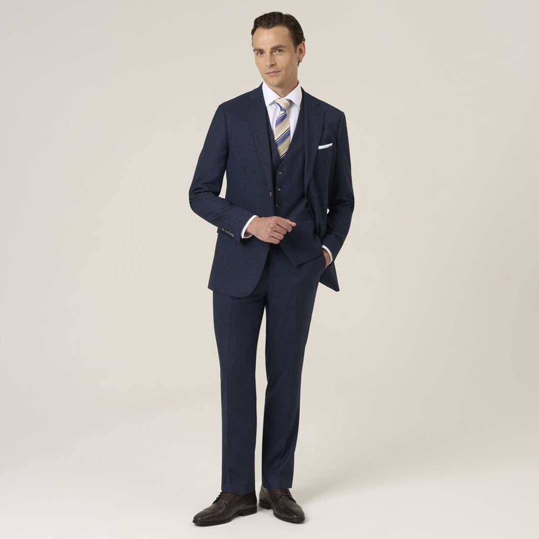 Man wearing a navy blue suit with a white shirt and striped tie on a light background