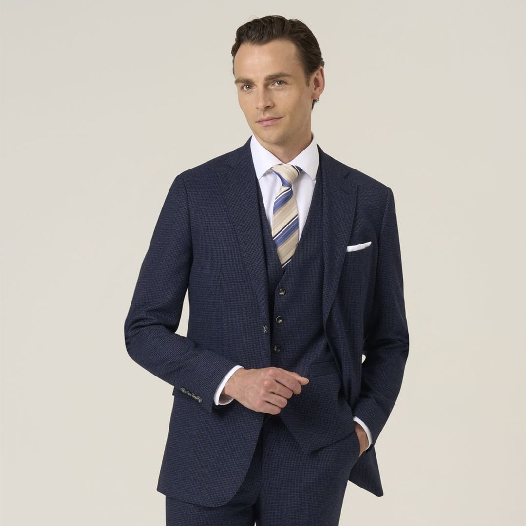 Man wearing a navy blue suit with a striped tie on a light background