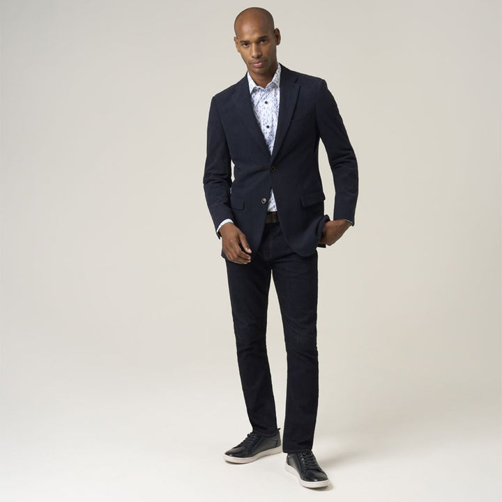 Man wearing a navy suit with a white shirt on a plain background