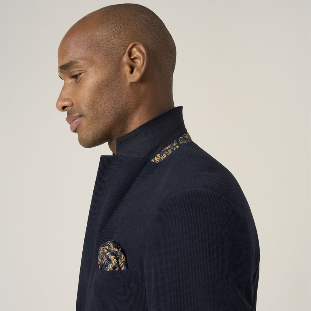 Man wearing a navy sweater with floral patterns on a plain background