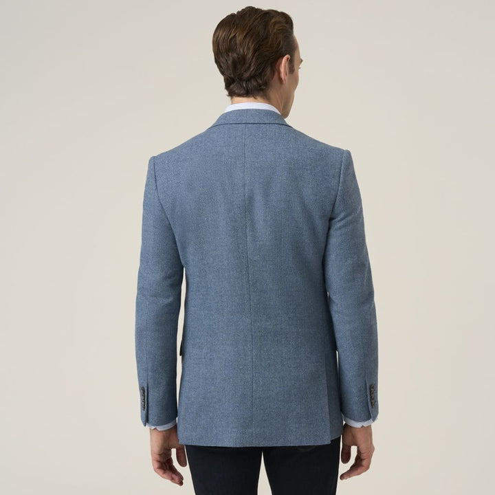 Man wearing a blue blazer from behind on a plain background