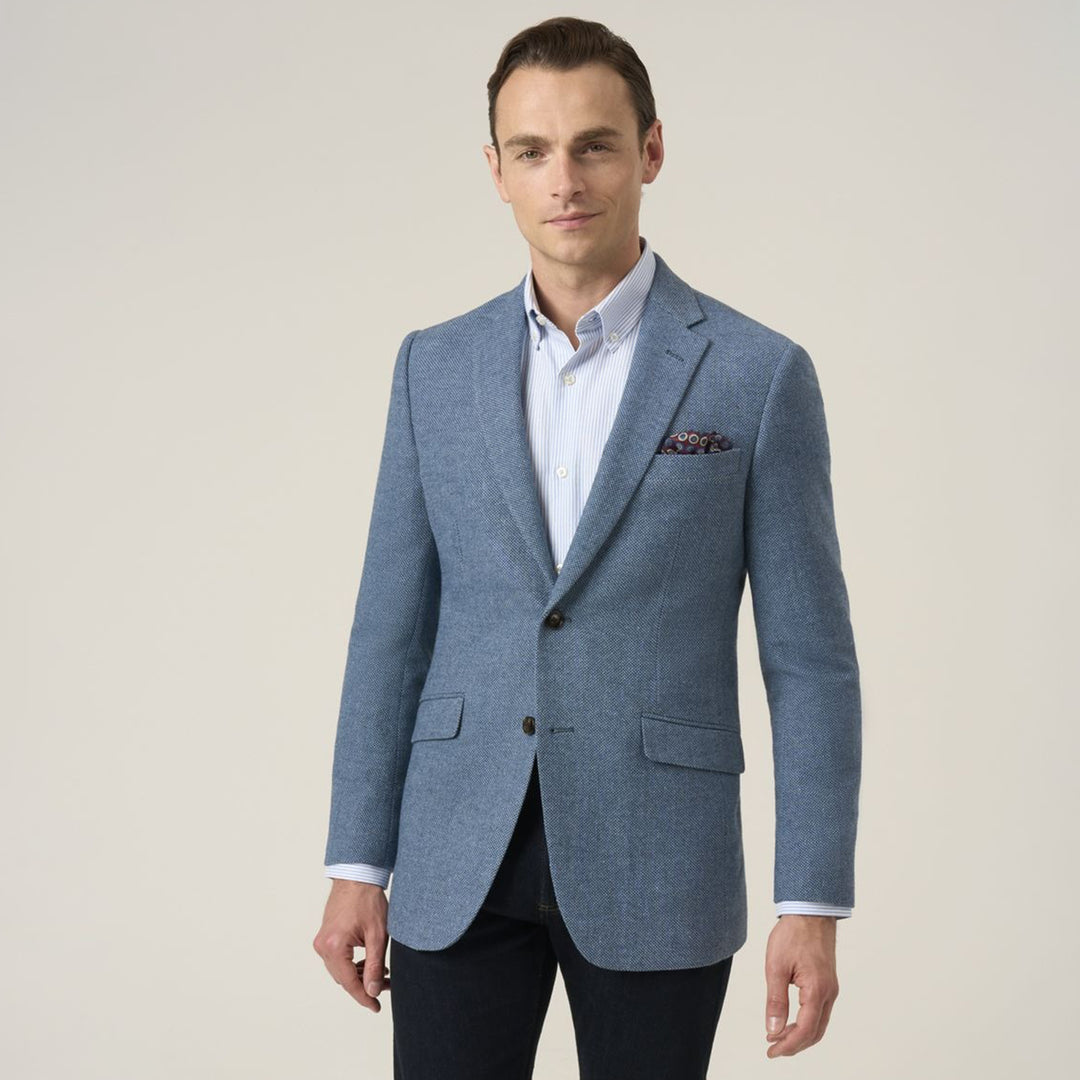 Man wearing a blue blazer over a white shirt on a beige background