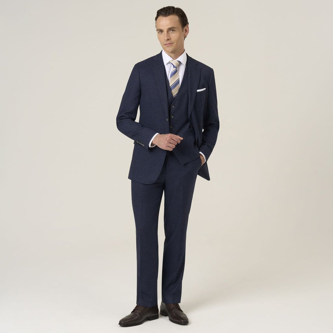 Man wearing a navy blue suit with a white shirt and striped tie on a light background
