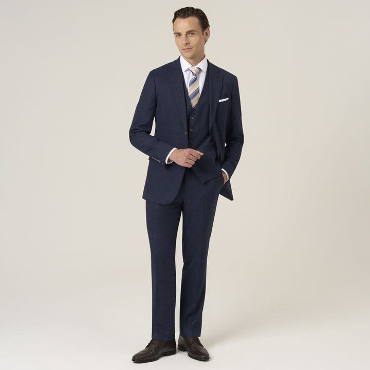 Man wearing a navy blue suit with a white shirt and striped tie on a light background