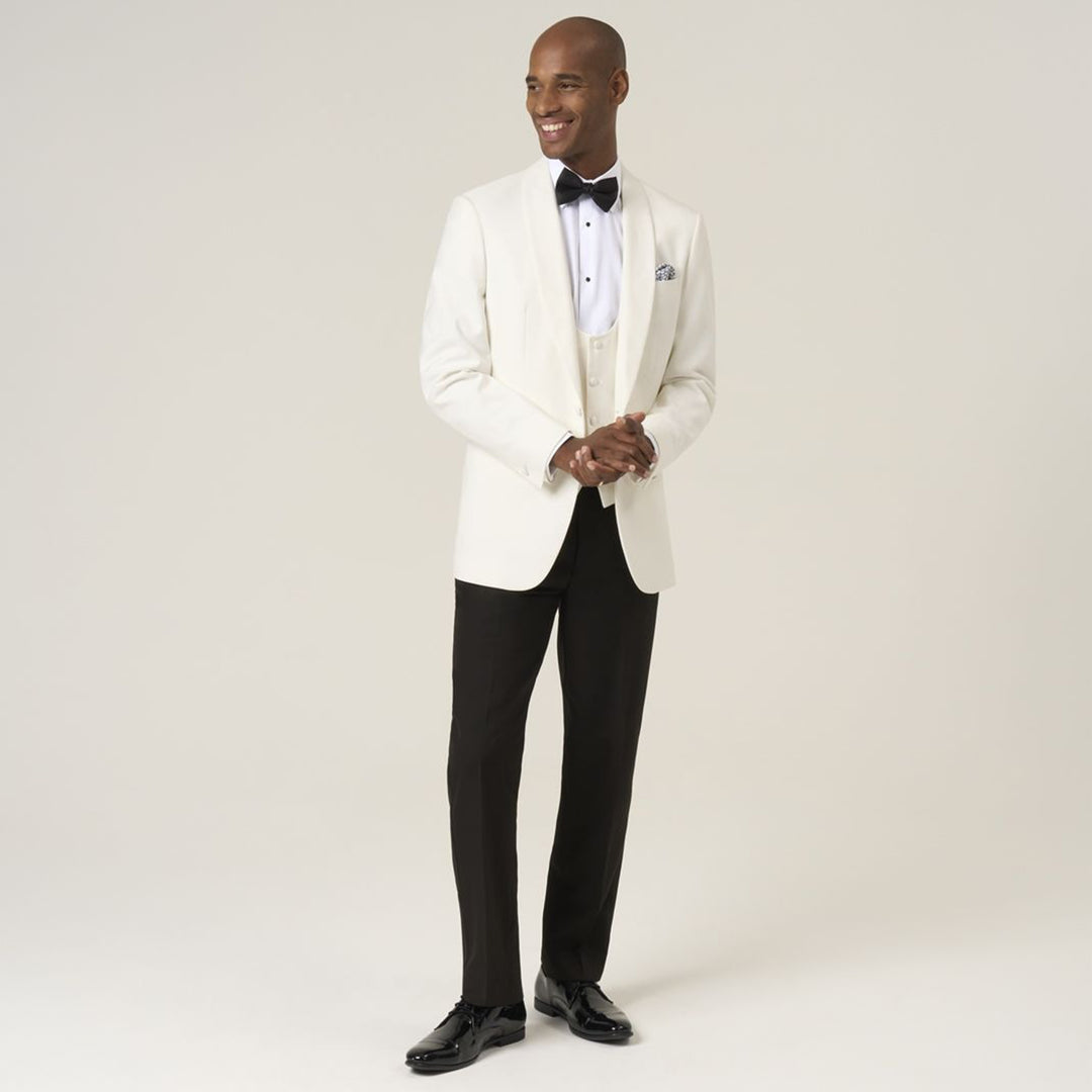 Man wearing a white tuxedo with black pants on a plain background