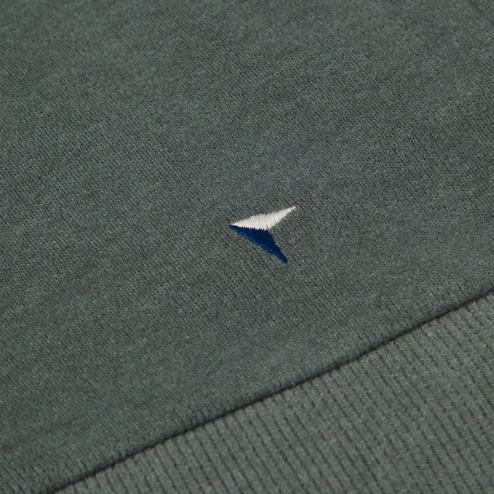 Close-up of a textured fabric surface with a small embroidered logo.