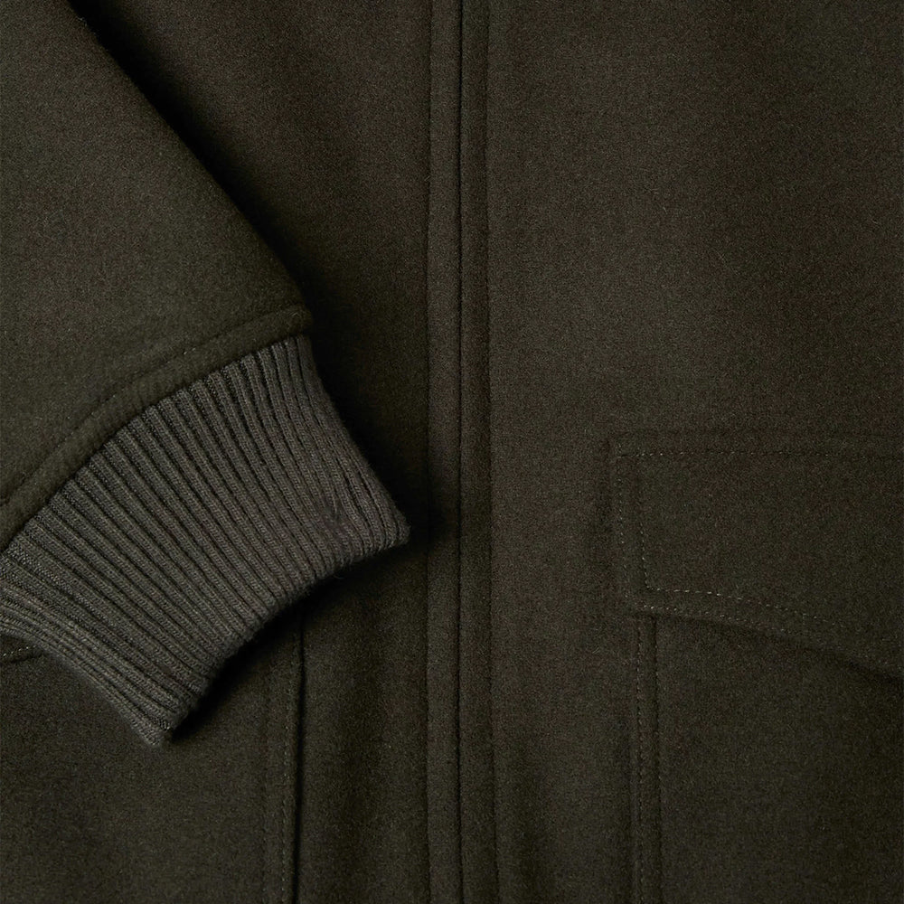 Close-up of a dark green jacket with a ribbed sleeve and pocket detail.