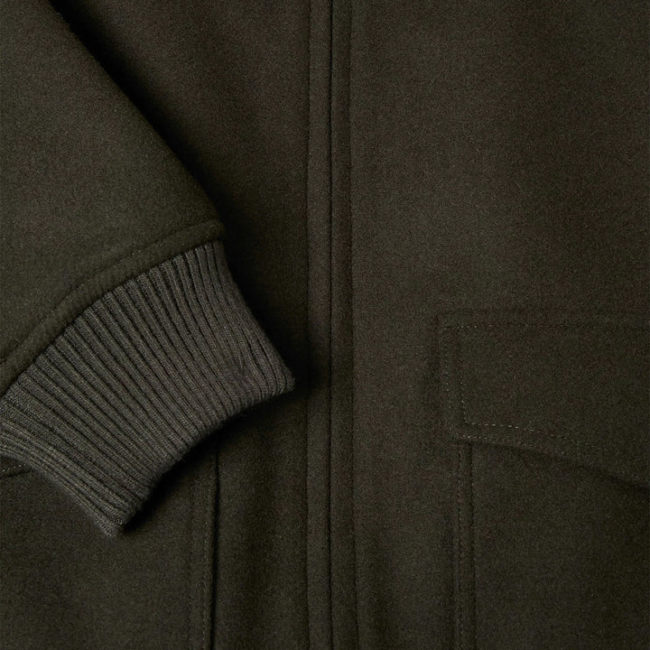 Close-up of a dark green jacket with a ribbed sleeve and pocket detail.