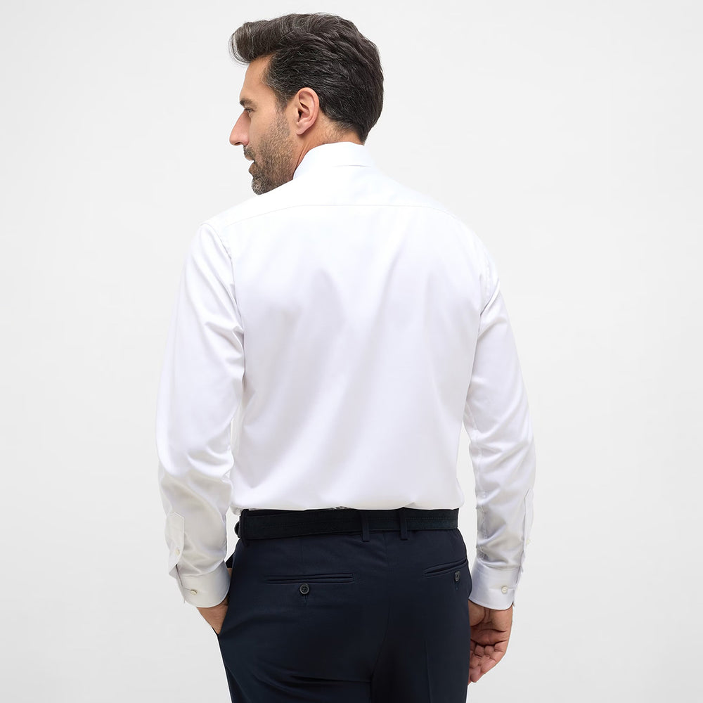 Man wearing a white dress shirt and dark pants on a light gray background