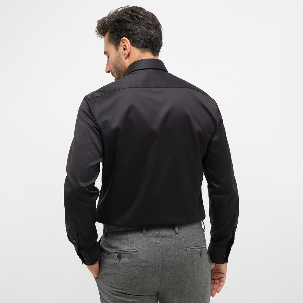 Man wearing a black dress shirt and gray pants on a white background