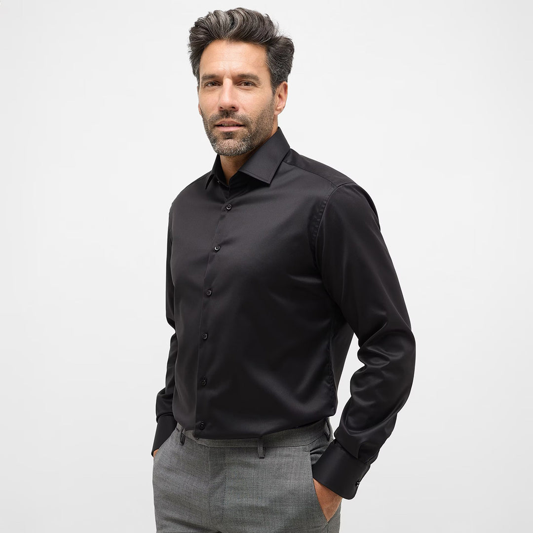 Man wearing a black dress shirt and gray pants on a white background
