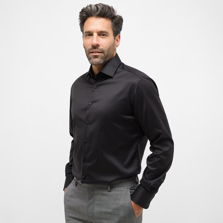 Man wearing a black dress shirt and gray pants on a white background