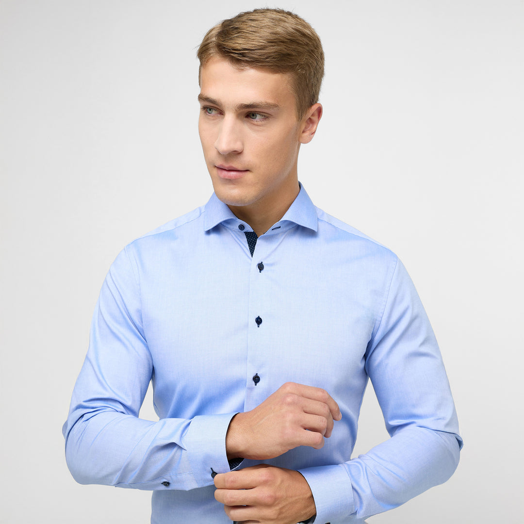 Man wearing a light blue dress shirt against a plain background