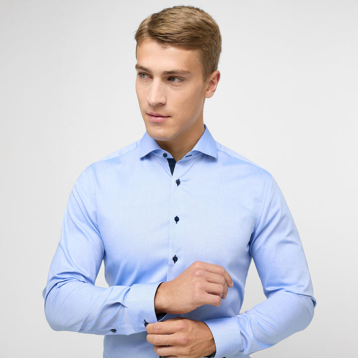 Man wearing a light blue dress shirt against a plain background