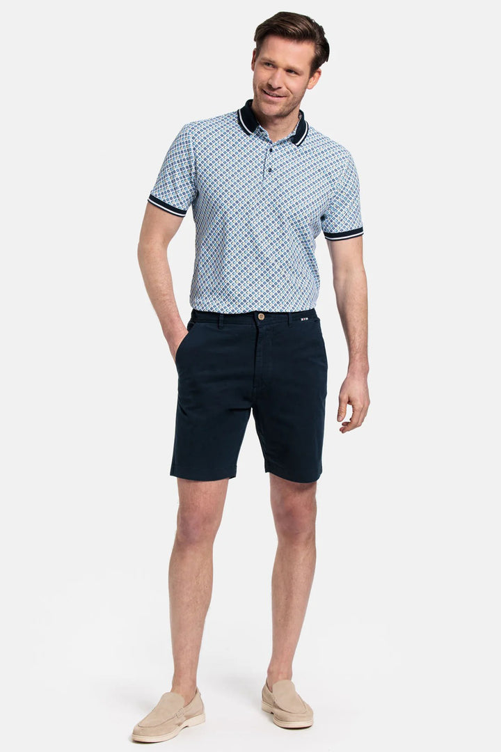 Man wearing a patterned polo shirt and navy shorts on a white background