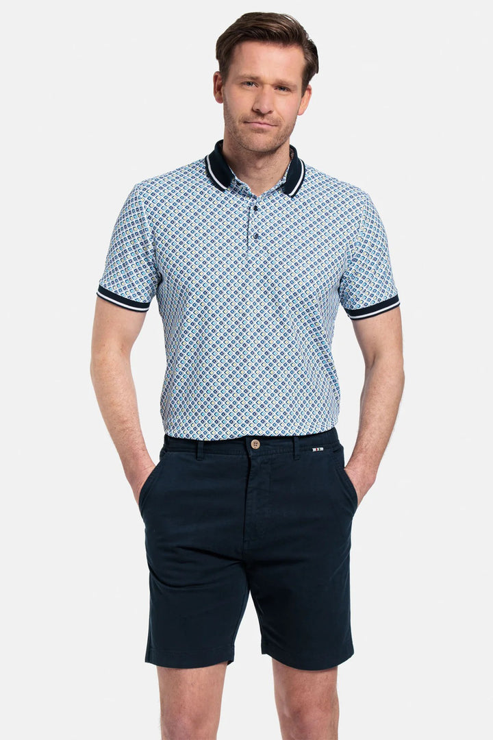 Man wearing a patterned polo shirt and navy shorts on a light gray background