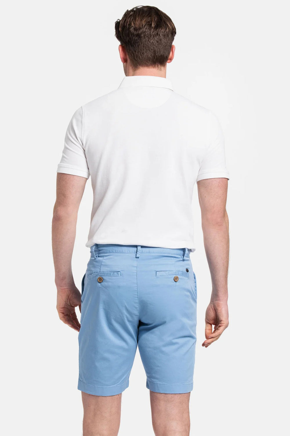 Man wearing light blue shorts and a white polo shirt on a white background