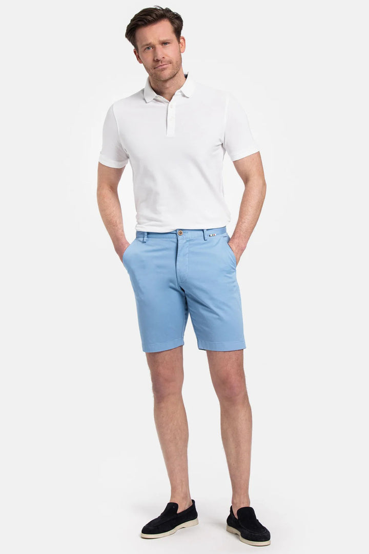Man wearing a white polo shirt and light blue shorts on a white background