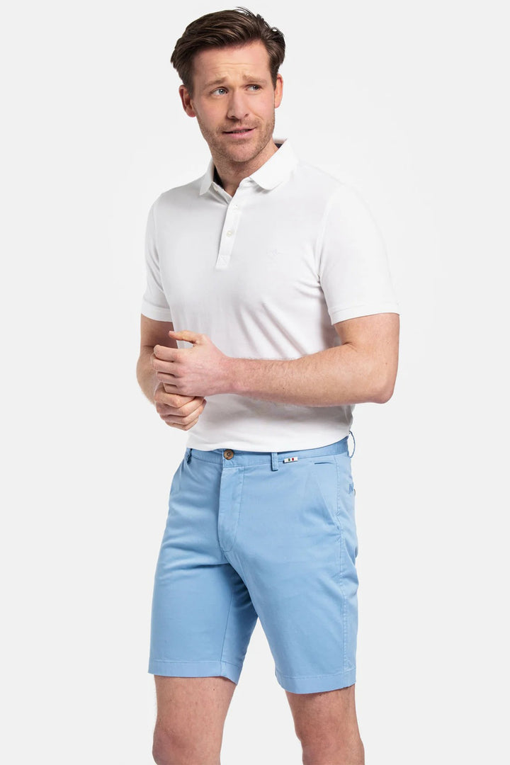 Man wearing a white polo shirt and light blue shorts on a white background