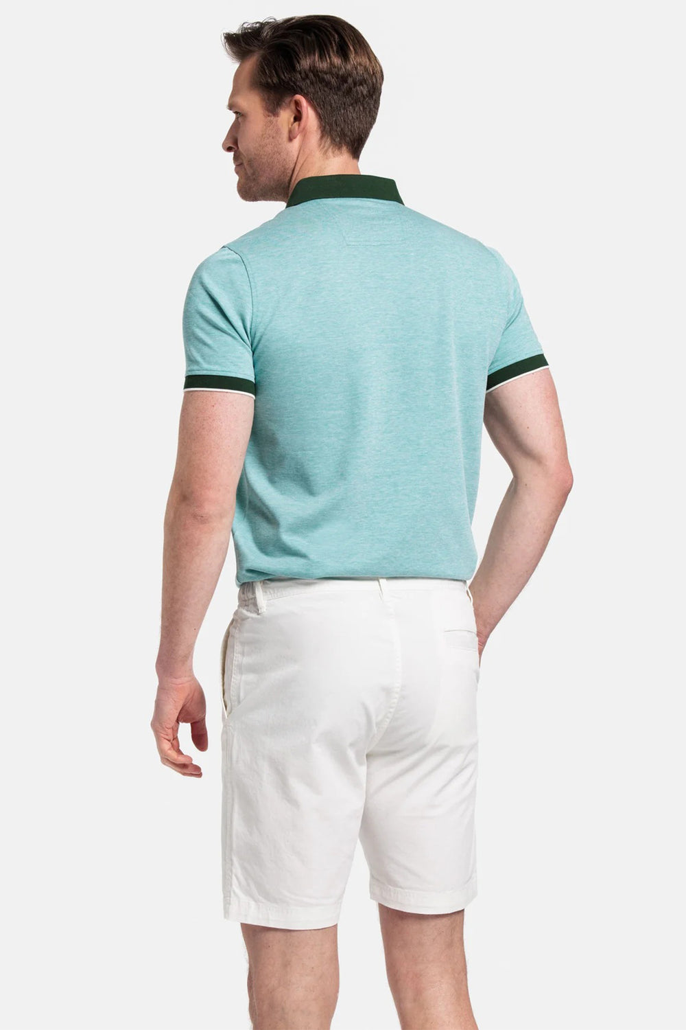 Man wearing a light blue polo shirt and white shorts on a white background