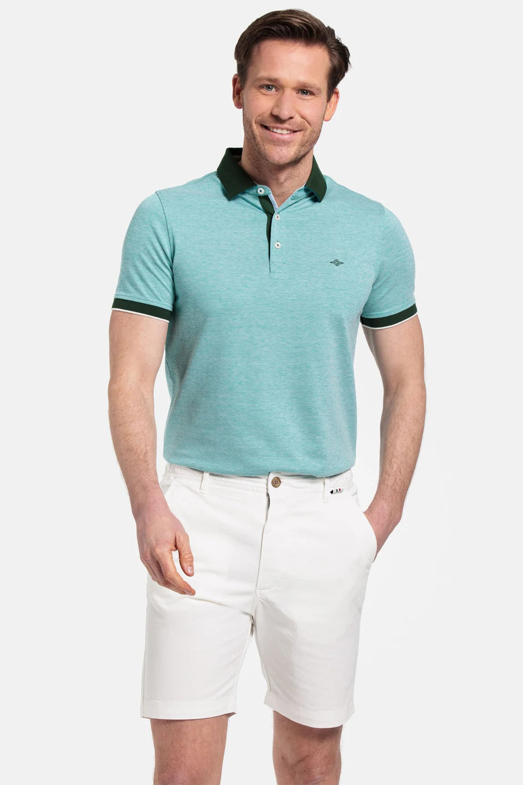 Man wearing a teal polo shirt with black trim and white shorts on a light gray background