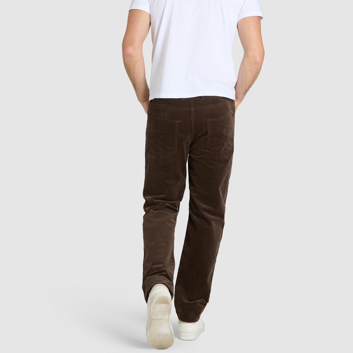 Person wearing brown pants and white shoes on a plain background
