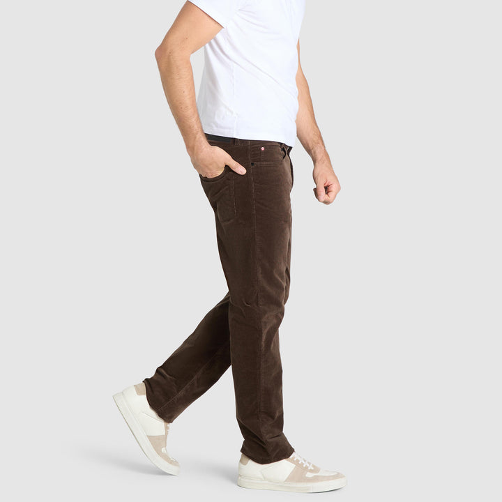 Person wearing brown pants and white sneakers on a light gray background