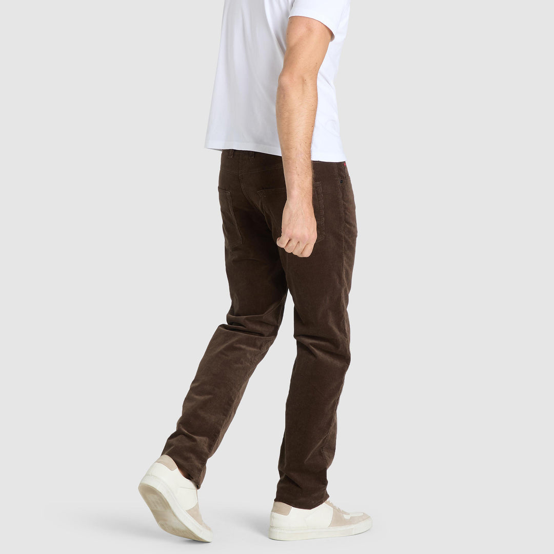Person wearing brown pants and white shoes on a plain background