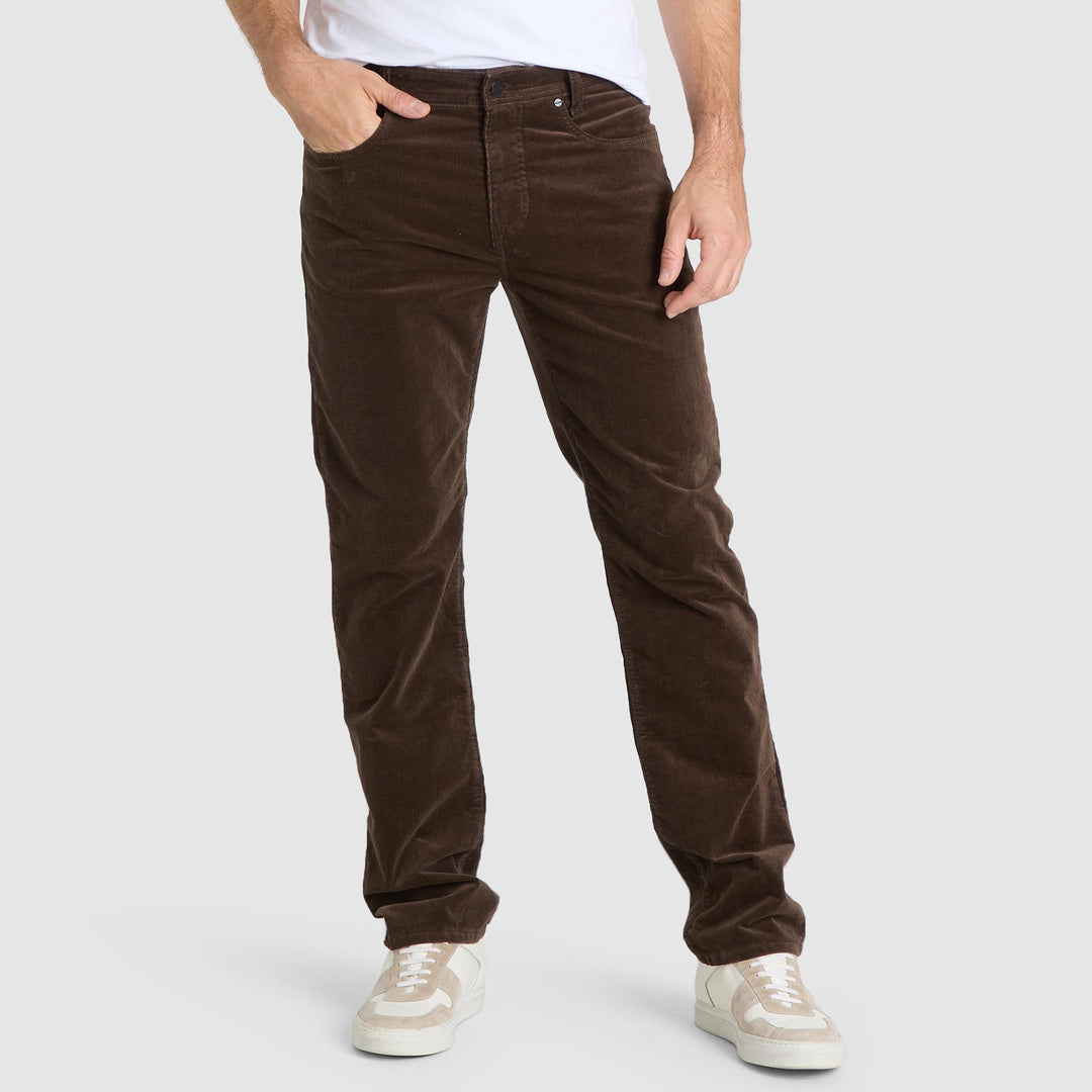 Brown corduroy pants worn by a person on a white background