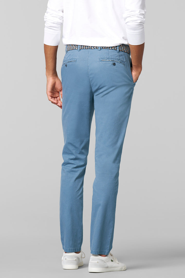 Person wearing light blue pants and a white shirt on a gray background