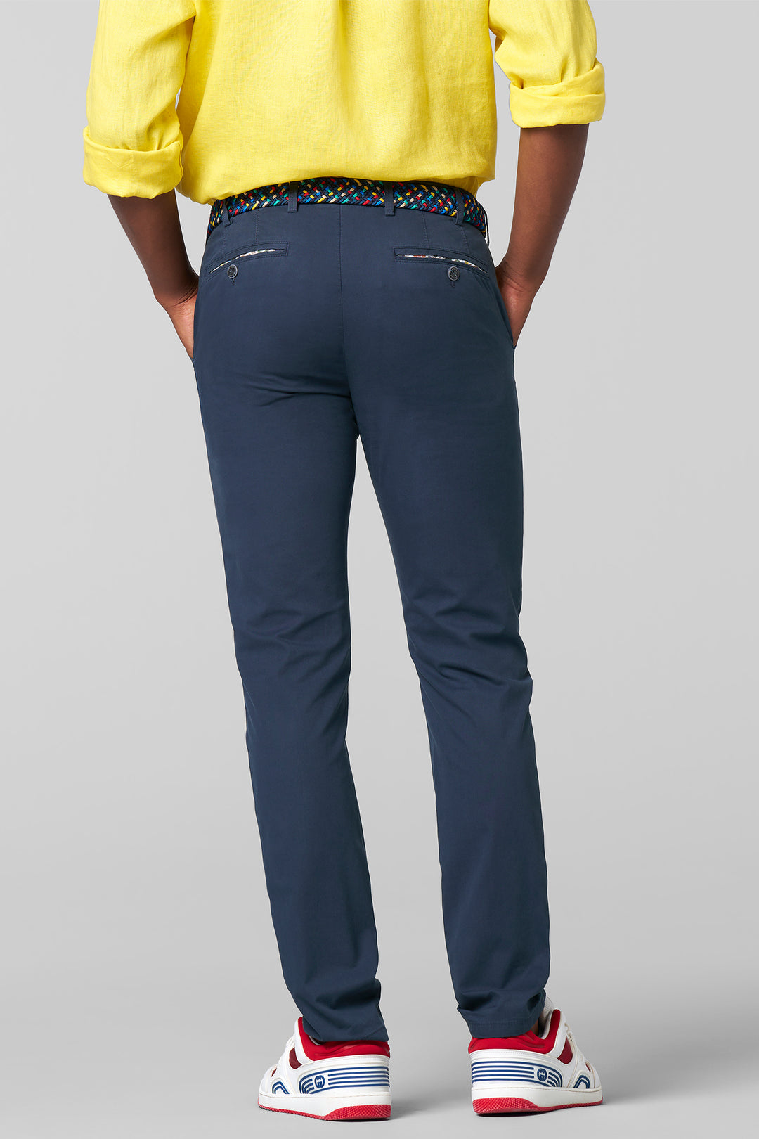 Person wearing navy pants with a yellow top on a gray background