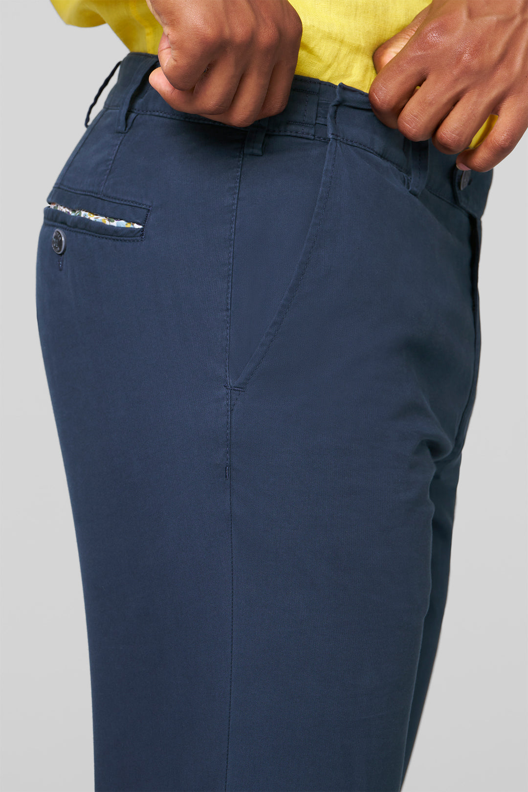Navy blue pants with a pocket detail on a gray background