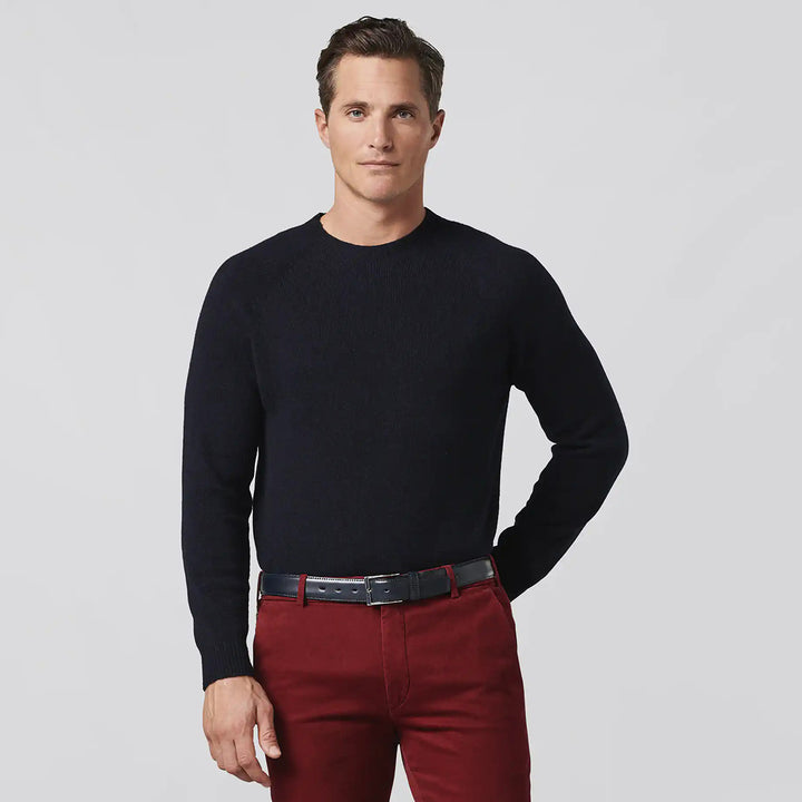 Man wearing a black sweater and red pants on a light gray background