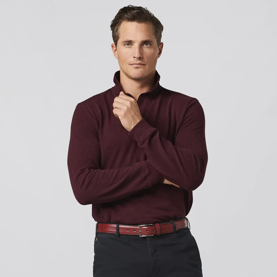 Man wearing a burgundy long-sleeve shirt with a plain background