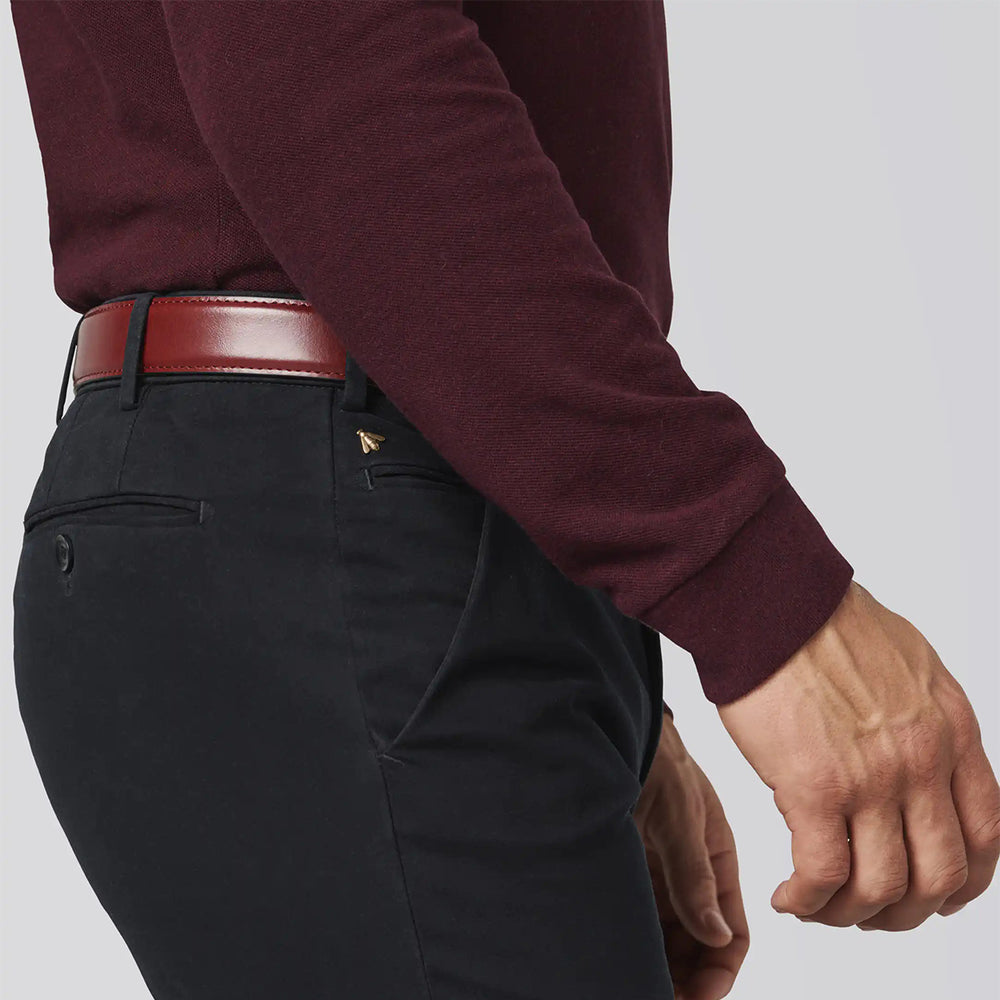 Person wearing a burgundy long-sleeve shirt and black pants with a red belt on a light gray background