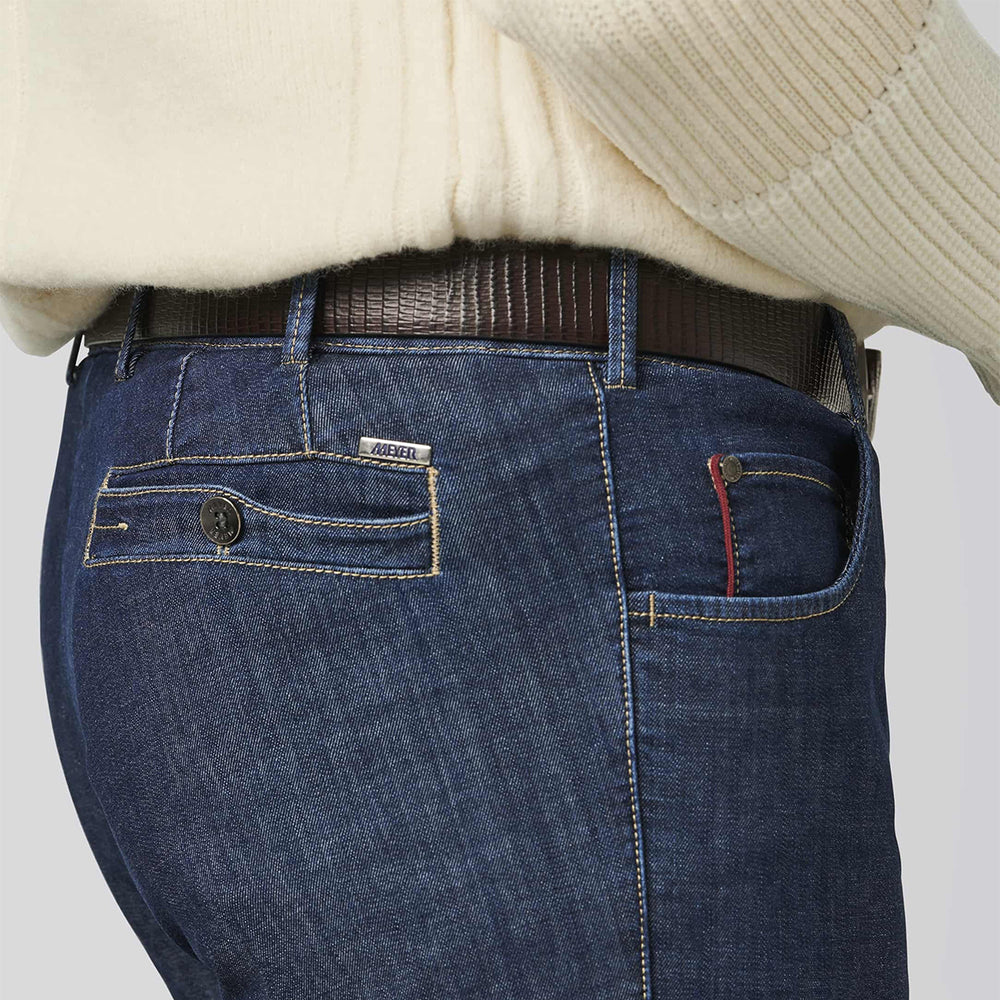 Close-up of blue jeans with a brand label on a light gray background