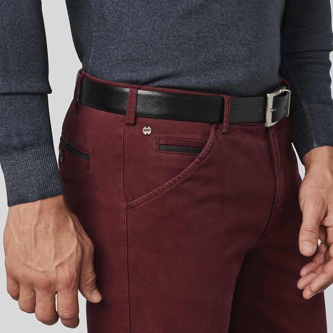 Maroon pants with a black belt worn by a person on a light gray background