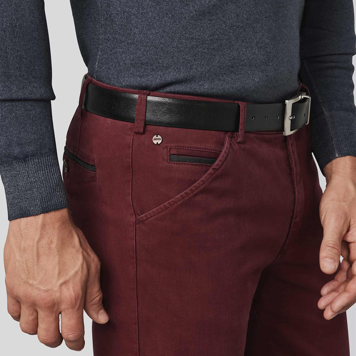 Maroon pants with a black belt worn by a person on a light gray background