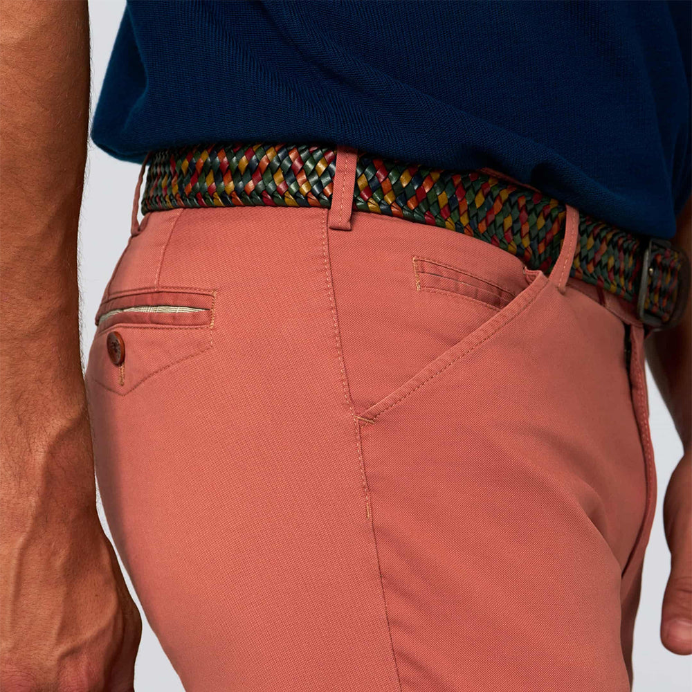 Person wearing a colorful belt with pink pants on a light gray background